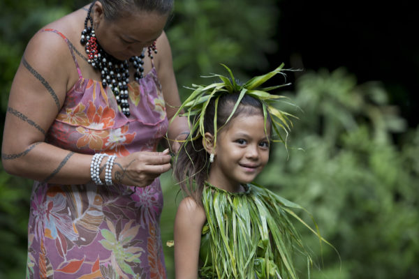 Polynesian woman making traditional costum on her daughter